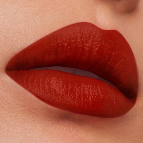 Nahaufnahme von rotem Lippenstift auf vollen Lippen, zeigt glatte Haut und einen kleinen Teil der Zähne.