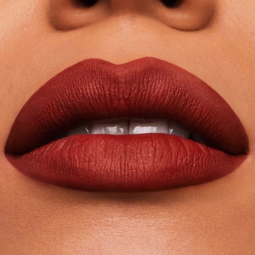 Close-up van lippen met donkerrode lipstick en licht zichtbare tanden.