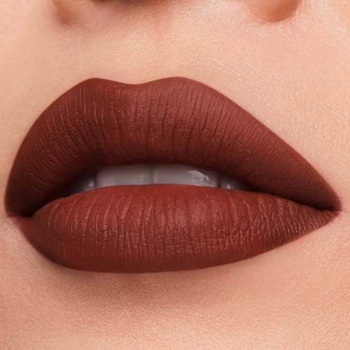 Close-up van lippen met matte bruine lippenstift, licht open en tanden zichtbaar.