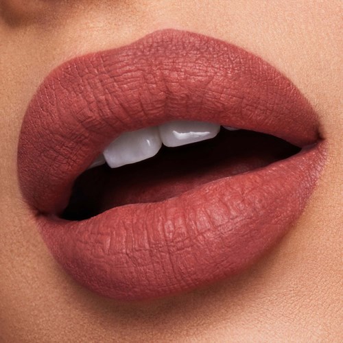 Close-up van lippen die lichtjes geopend zijn, met witte tanden, met matte lipstick in een natuurlijke kleur.