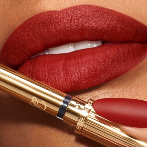 Close-up van lippen met rode lippenstift en een goudkleurige lippenstift. Lippen licht gespreid, witte tanden zichtbaar.
