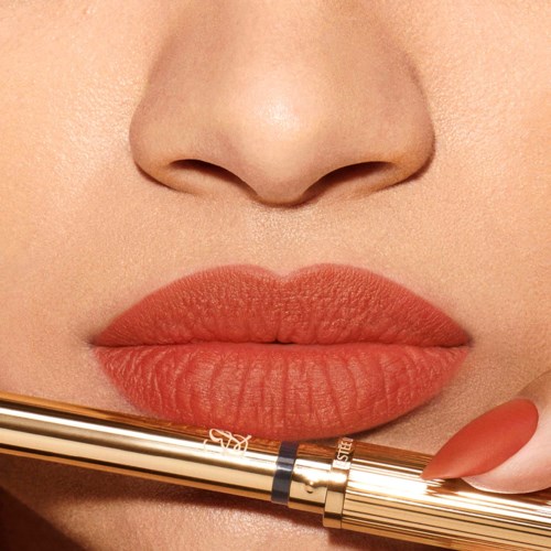 Close-up of lips being colored with lipstick, and a pen held near the lips.