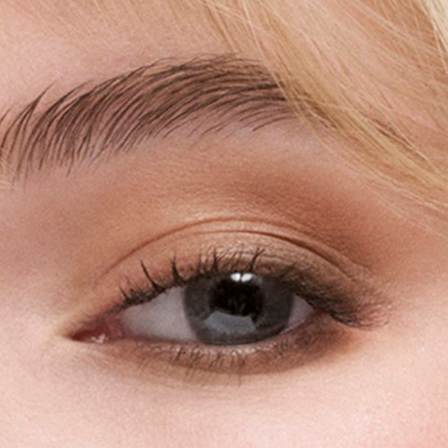 Close-up van iemands oog met lichte make-up, lichte wenkbrauw en reflectie in de pupil.