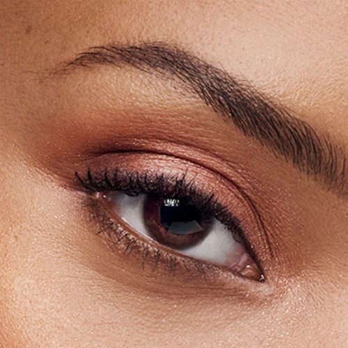 Close-up van iemands oog met make-up, met wimpers, wenkbrauw en bruine iris.