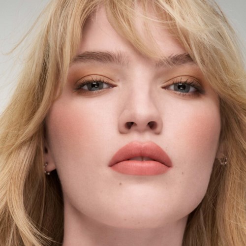 Close-up van een vrouw met blond haar, blauwe ogen en natuurlijke make-up. Ze ziet er zelfverzekerd en kalm uit.