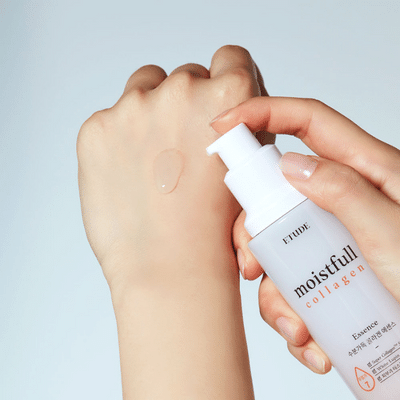 Een hand brengt een doorzichtige moisturizer of serum aan van een witte pompflacon op de achterkant van de andere hand.