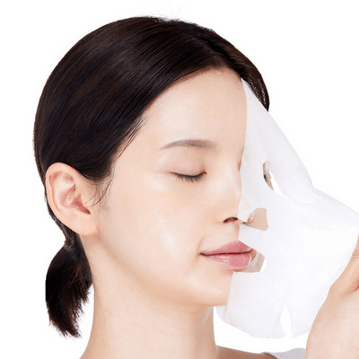 Een vrouw houdt een gezichtsmasker dicht bij haar gezicht met haar ogen gesloten.