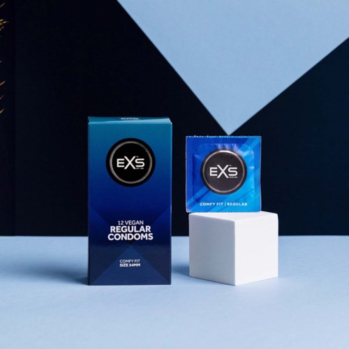 Eine Schachtel und ein Kondomverpackung mit der Marke EXSs auf einem weißen Ständer vor dunklem und blauem Hintergrund.