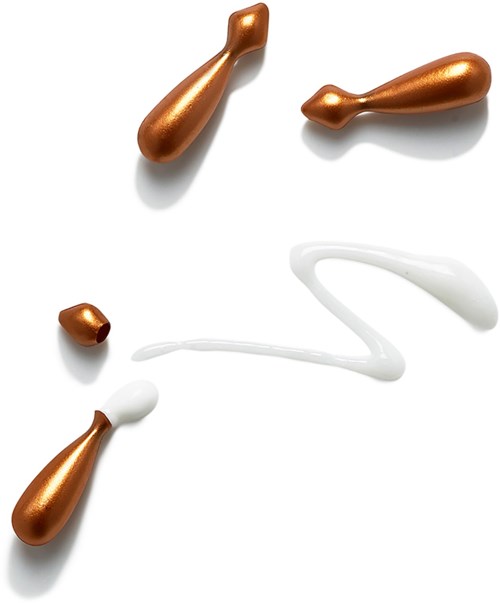 Tropfen aus kupferfarbener und weißer Creme oder Lotion, künstlerisch angeordnet auf weißem Hintergrund.