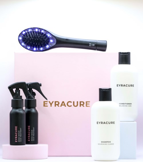 A set of cleaning products with spray bottles, shampoo, conditioner, and a brush on a pink box.