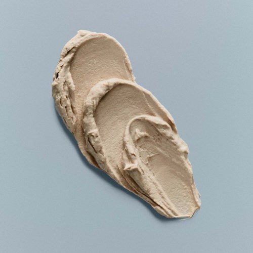 Drie beige kleimaskers liggen op elkaar op een lichte grijze achtergrond.