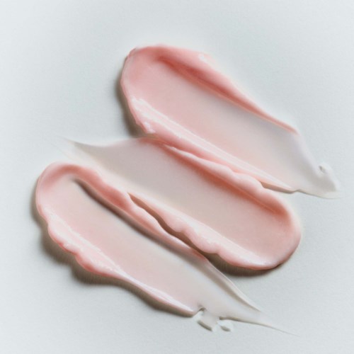 Three streaks of pink and white cream on a light background.