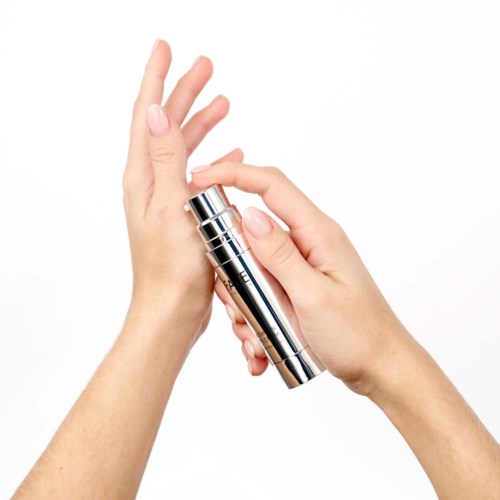 Een persoon brengt crème of lotion aan met een zilverkleurige pompflacon op hun hand.