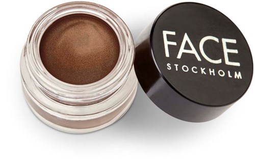 Een kleine pot met bruine gezichtsmake-up en een zwarte deksel met 'FACE STOCKHOLM'.