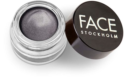 En liten burk med mörk, metallisk ansiktsmakeup märkt 'FACE STOCKHOLM' med locket bredvid.