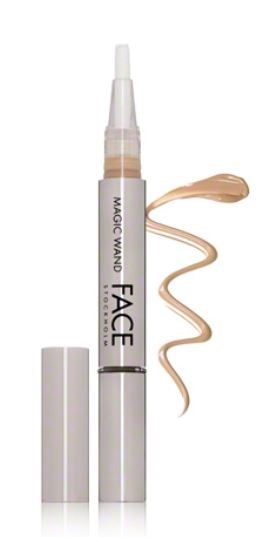 En vit concealer-penna med beige vätska och kam-ände, bredvid sitt lock.