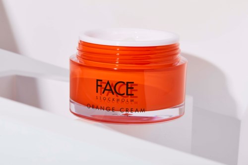 Een pot oranje crème van FACE Stockholm op een witte ondergrond met lichte schaduwen.
