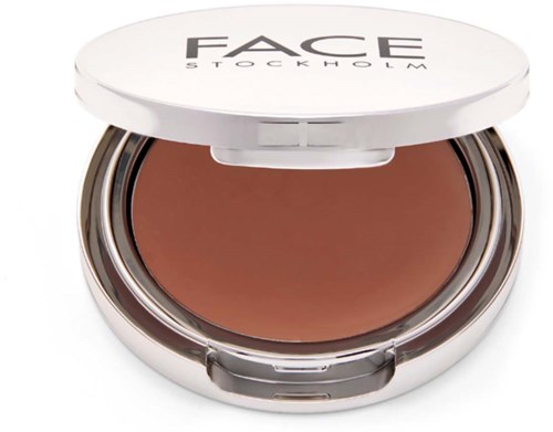 En liten dosa med ansiktsmakeup, märkt 'FACE STOCKHOLM,' med brunt kräm eller puder inuti.