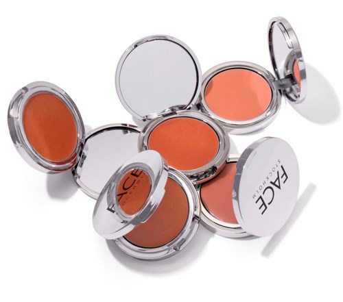 Flera öppna puder- eller rougeaskar med persikofärgad makeup inuti, märkta med FACE.