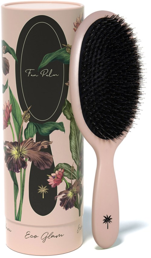 A hairbrush with black bristles and a light pink handle, next to a tall, decorative box with floral and plant designs.