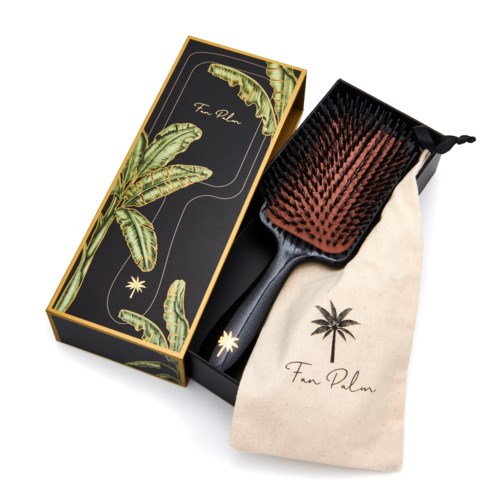 A hairbrush with a wooden handle, a box with banana leaf design, and a cloth bag with a palm tree logo.