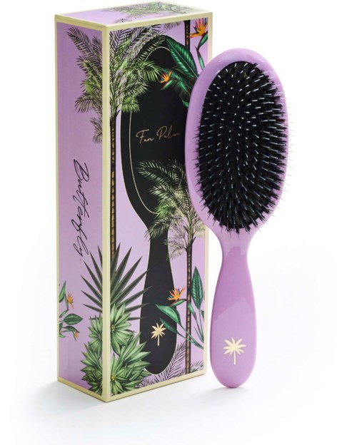 A pink hairbrush with black bristles next to a colorful tropical-themed box.