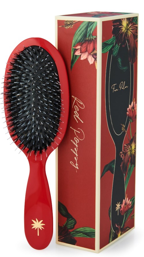 A red hairbrush with black bristles and a floral box featuring colorful flowers and leaves.