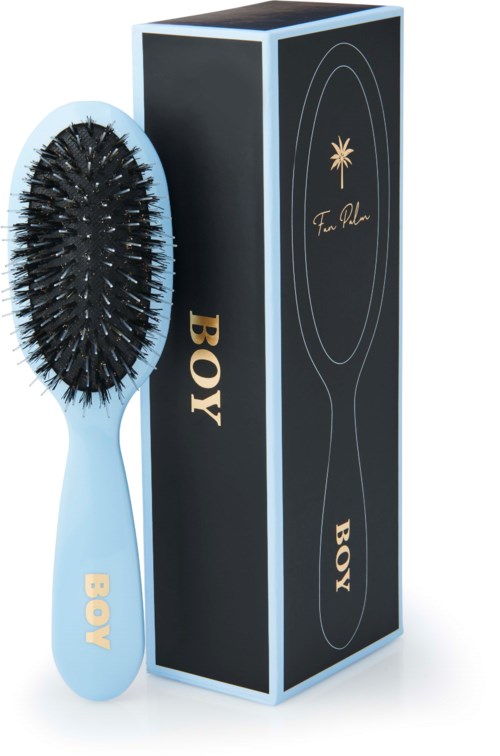 A blue hairbrush with black bristles next to a black box labeled 'BOY' and 'Tom Ford' logo.