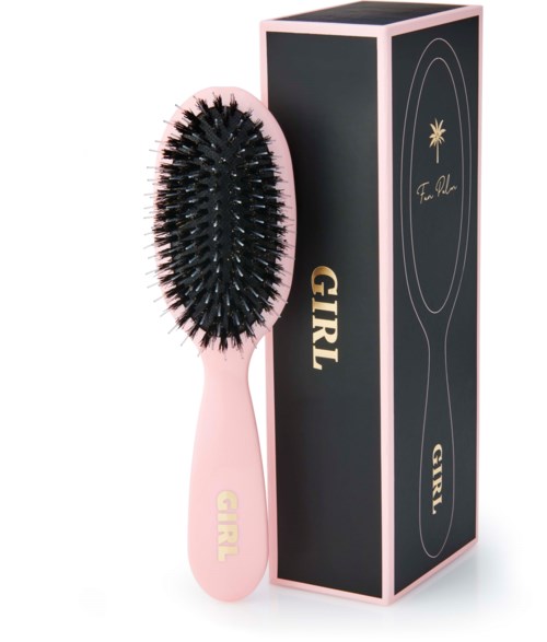 A pink hairbrush with black bristles standing beside a black and pink box.