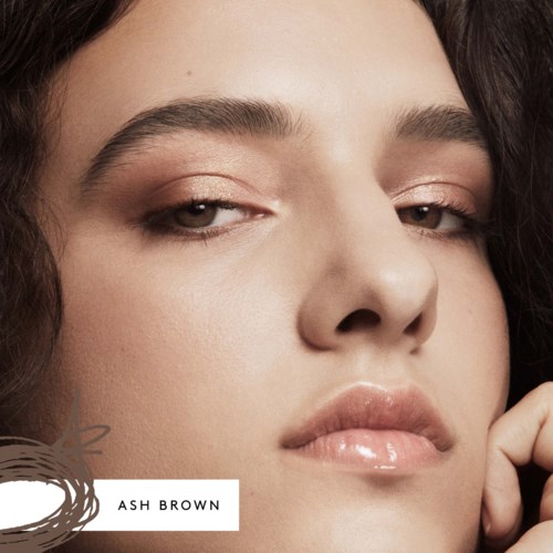 Close-up of a woman with smooth skin, full lips, and slightly squinting eyes, looking confident and relaxed.