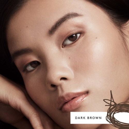 Close-up of a woman's face with dark brown hair and smooth skin.