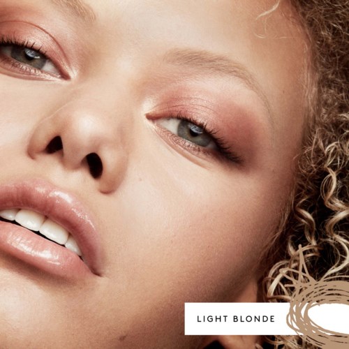 Close-up of a light blonde woman with curly hair, showing her face and makeup details.
