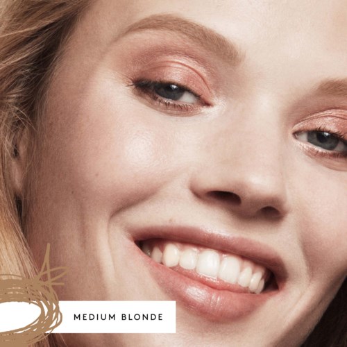 Close-up of a smiling woman with light makeup, medium blonde hair, and visible teeth.