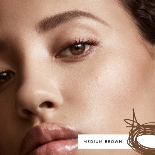 Close-up of a woman's face showing smooth skin, brown eyes, and full lips, with a label indicating medium brown skin tone.