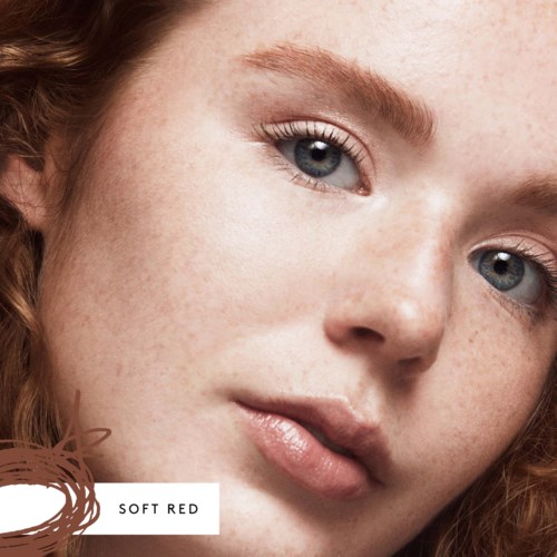 Close-up of a young woman's face, fair skin with freckles, blue eyes, and natural makeup, soft red hair.