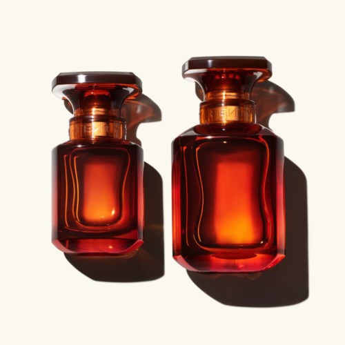 Two red glass bottles with black caps, casting shadows on a light background.
