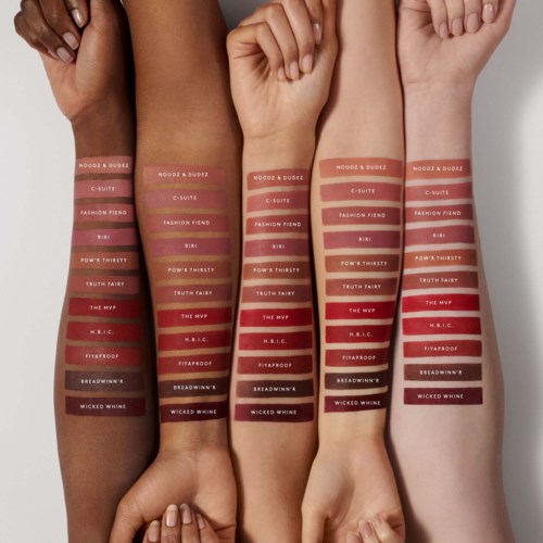 Four arms with skin tones ranging from dark to light, each painted with lipstick test colors and labels.