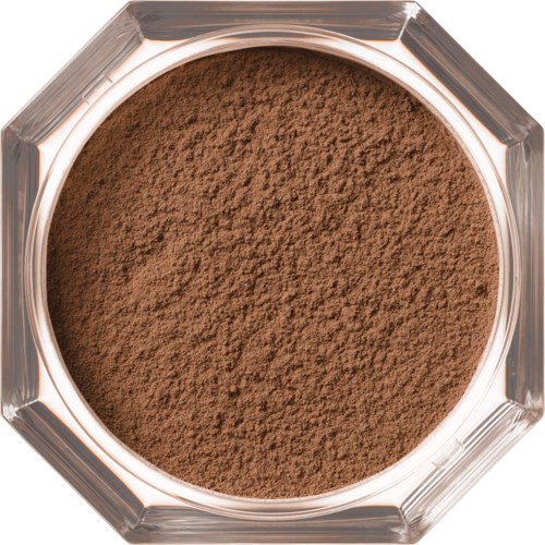 A round container filled with brown powder, seen from above. The container is clear with a geometric edge.