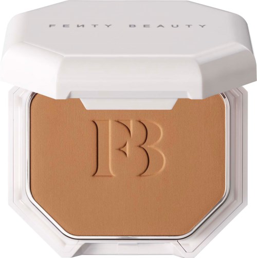A compact makeup powder case with a beige powder and embossed initials 'TB'. The case has a white lid labeled 'Fenty Beauty.'