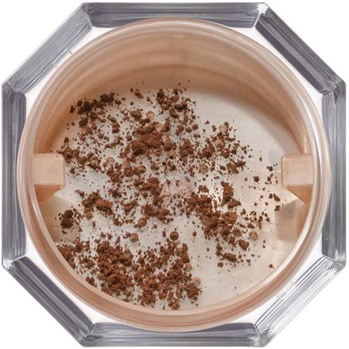 A jar has beige powder with brown specks, seen from above with a clear glass container.