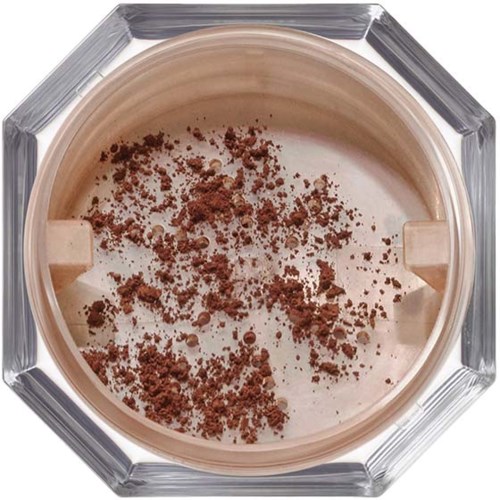A round container with beige cream and brown powder on top, inside a facedown octagonal glass holder.