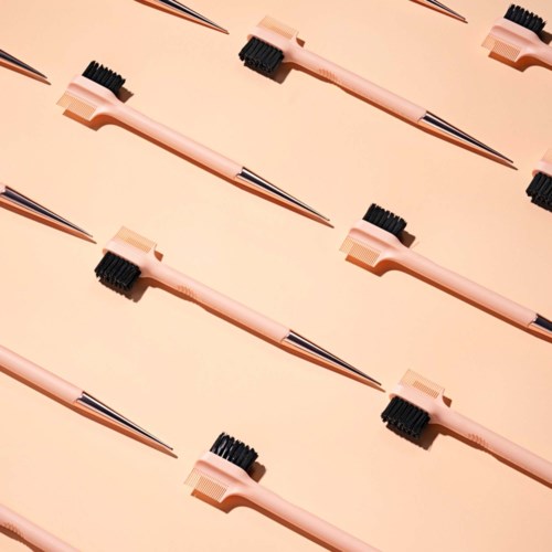 A pattern of tweezers and small brushes arranged diagonally on a beige background.