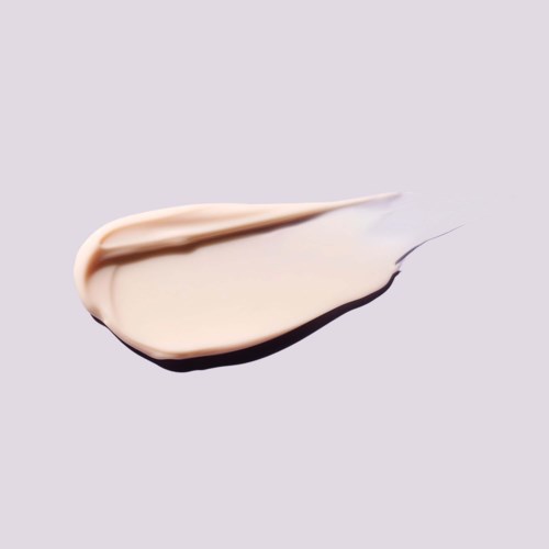 A smear of light beige cream with a darker shadow underneath on a plain, light gray background.
