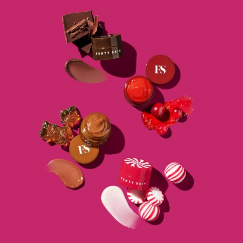 Various Fenty Skin skincare and makeup products with red and brown packaging on a pink background.