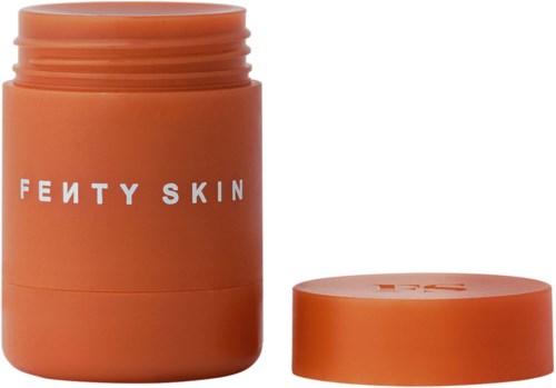 A large orange jar with a separate lid and white text, labeled Fenty Skin, appears to be a skincare product.