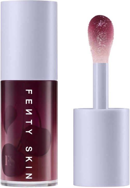 Lip gloss with a dark red color and a white cap, open applicator brush beside it.
