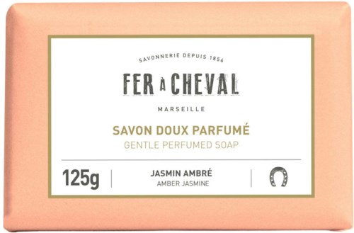 A soap package with a pink color, gold and white text, and a note about amber jasmine scent and gentle perfume.