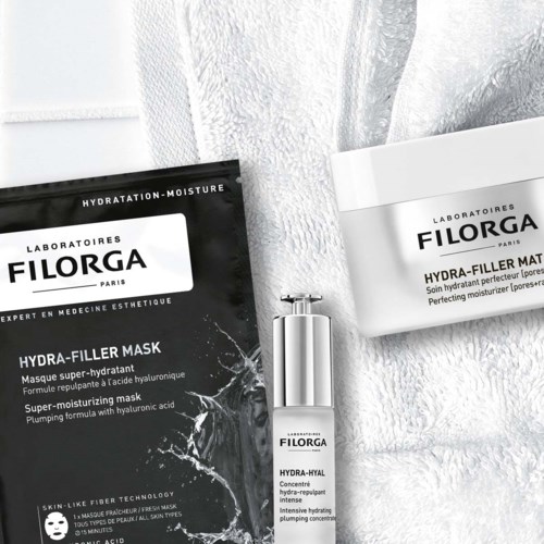Två hudvårdsprodukter: ett svart paket märkt Hydra-Filler Mask och en vit flaska som heter Hydra-Hyal. De ligger på en handduk.