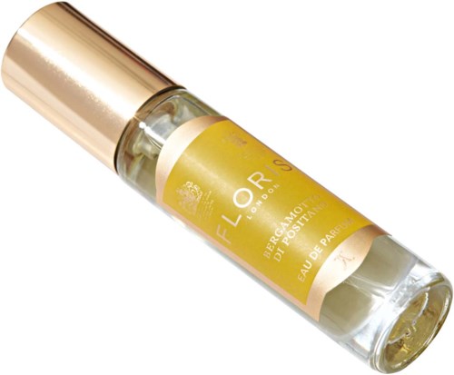 Een kleine parfumfles met goudkleurige dop en gele etiket, ligt schuin. Bevat Eau de Parfum. Elegant en simpel ontwerp.