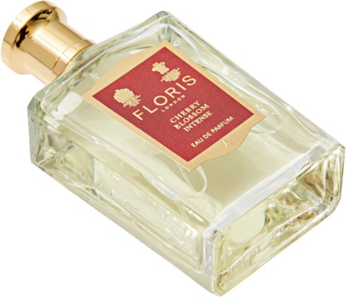 Een parfumfles met label 'FLORE' met kersenbloesem en vanillegeur, gouden dop en helder glas.